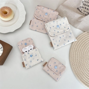 Detailed view of floral fabric pouch holding wireless earbuds with a snap button