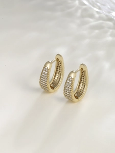 Detailed close-up of golden U-shaped earrings with pave-set white cubic zirconia stones
