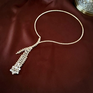 Macro shot of gold tassel necklace with marquise zircons on deep red satin fabric