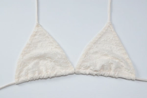 Vue détaillée de la dentelle blanche et des motifs floraux sur un haut de bikini triangle
