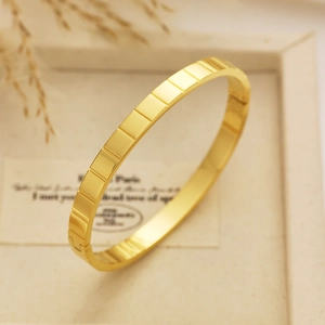 Dettaglio di un bracciale in acciaio inossidabile dorato con trama geometrica a quadri
