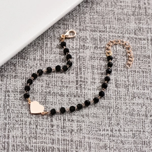 Minimalist black faceted bead bracelet with a polished gold heart charm and adjustable chain