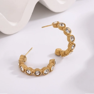 Detail of C-shaped gold-plated stainless steel earrings with sparkling round zirconia stones