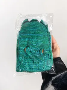 Detailed close-up of green knitted crocodile socks with decorative button eyes and teeth