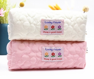 Close-up of quilted floral texture and Lucky Flower label on white and pink stationery bags