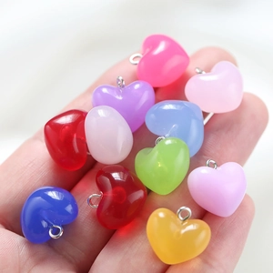 Close-up of colorful acrylic heart pendants in hand showing glossy finish and metal hooks