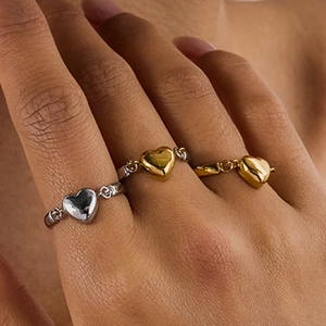 Close-up of 18K gold and silver reversible heart chain rings on a model's hand