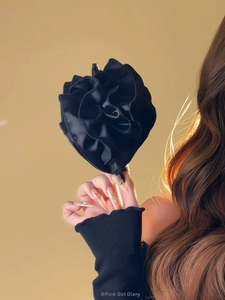 Gros plan d'une grande pince à cheveux fleurie noire plissée sur une coiffure élégante