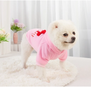 Pink dog hoodie with red bow and 'pretty' embroidery shown in a cozy home setting
