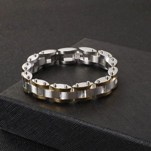 Detail of mixed gold and silver stainless steel chain bracelet on black texture box