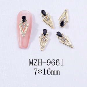 Macro detail of alloy nail charms featuring black teardrop stones in golden hollow frames