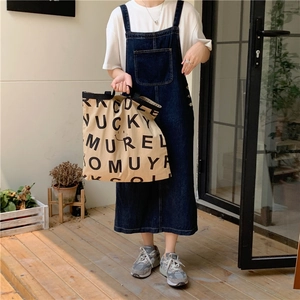 Detail der hellbraunen Canvas-Tasche mit Smiley und Buchstaben an einem Model