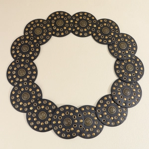 Detailed macro view of retro black leather circles with golden rivets and embossed buckles