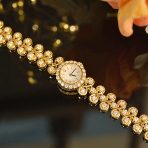 Macro view of luxury vintage gold watch with crystal encrusted bracelet on dark background