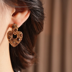 Gros plan sur des boucles d'oreilles cœur vintage dorées avec strass ambrés