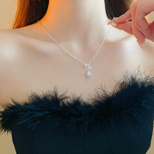 Close-up of a minimalist silver paperclip chain necklace with a spherical pearl pendant