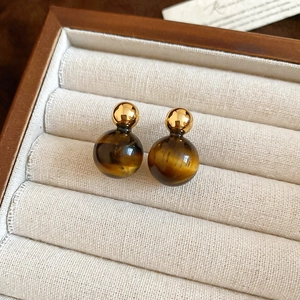 Close-up of tiger eye stone drop earrings with gold metallic beads in a beige jewelry box