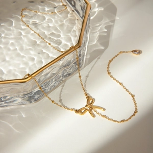 Detail of 18k gold plated Y-necklace with bow pendant in a ripple glass tray