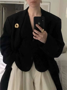 Minimalistische goldene Sicherheitsnadel-Brosche auf einem schwarzen Oversize-Blazer