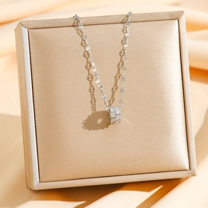 Elegant silver necklace with a cylinder zircon pendant displayed on a gold jewelry card