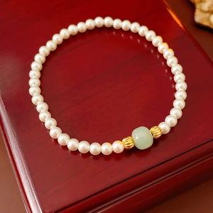 Macro detail of pearls and green Hetian jade bead on vintage red wood texture