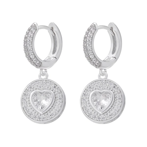 Gros plan de boucles d'oreilles créoles argentées avec pendentifs brillants en forme de cœur
