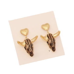 Vintage bull head earrings with gold heart studs on a pink card background