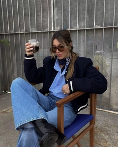 Dettaglio della giacca varsity vintage blu scuro con colletto a coste e outfit in denim