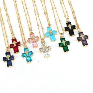 Close-up of colorful cross necklaces with vibrant zircons and beaded gold chains