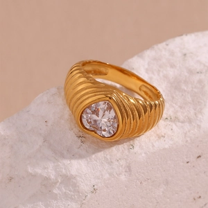 Detailed macro shot of 18K gold heart-shaped zircon ring on white textured stone
