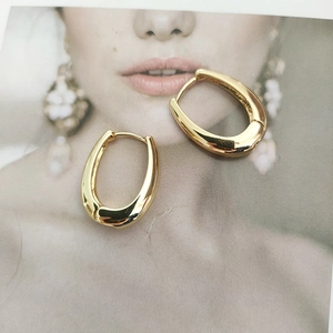Polished gold U-shaped metal hoop earrings displayed on a fashion magazine background