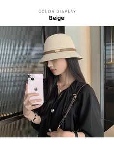 Dettaglio del cappello a secchiello beige con cinturino in pelle marrone e fibbia oro