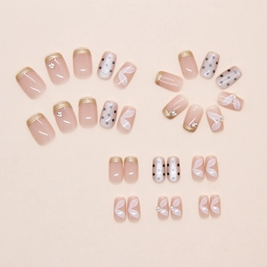 Detailed view of French-style dot press-on nails with gold edges and leaf patterns