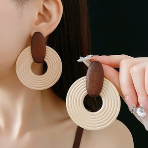 Gros plan sur de grandes boucles d'oreilles bohèmes en bois avec cercles beige et marron