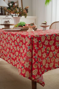 Detailed pattern of Christmas gingerbread man and houses on red linen festive tablecloth