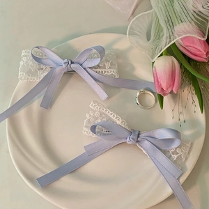 Detailed shot of white lace leg rings with light blue satin bows on a white plate