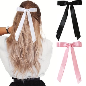 Detailed view of large satin bow hair clips in white black and pink colors