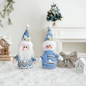 Close-up of blue knit Santa and snowman plush figurines in a snowy Christmas scene