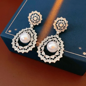 Detailed view of vintage silver stud earrings with zircon crystals and drop pearls