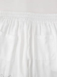 Detail of white trousers showing elastic waistband and square back pockets with neat stitching