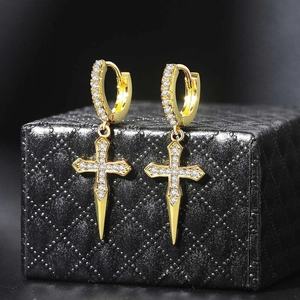 Close-up of gold dangle earrings with sparkling cubic zirconia cross pendants