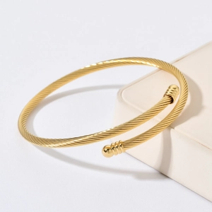 Macro detail of golden twisted cable bangle with spherical bead ends and woven texture