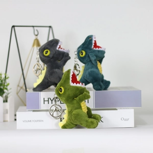 Three colorful plush dinosaur keychains in green, grey, and dark blue on a white display