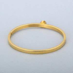 Dettaglio di un bracciale a cerchio dorato lucido con eleganti decorazioni cilindriche