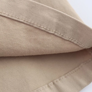 Macro shot of khaki cotton fabric with detailed single needle stitching on the hemline