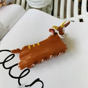 Detail of creative goat claw clip with acetate finish and golden horns on white magazine