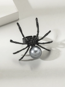 Dettaglio di un anello a ragno punk nero con perla grigia su sfondo grigio chiaro
