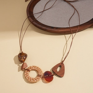 Détail d'un collier bohème avec anneaux en rotin tressé, pièces en bois et perles de résine