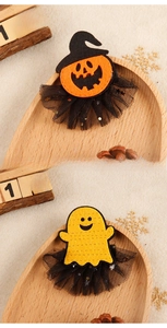 Detail of felt pumpkin and ghost hair clips with black mesh on a festive wooden tray