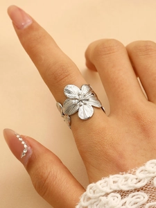 Macro shot of silver textured flower ring showing detailed petal design on hand